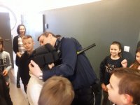 Policjant pokazuje dzieciom   jak zakladac na glowe kask ochrony dla zatrzymanego
