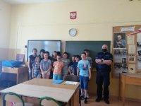 Dzielnicowy podczas spotkań z uczniami szkół. Dzieci stoją w klasie obok policjnat, oraz  zbiorowe zdjęcie przed budynkiem szkoły.