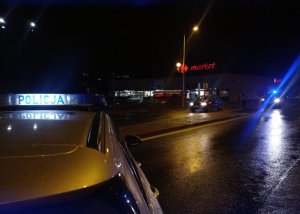 widok ze zdarzenia drogowego na ul Słowackiego w Opocznie. FOTO 1- volkswagen w kolorze ciemnym stoi na pasach w tle policjant wykonuje pomiary, foto nr 2 fragment radiowozu i perspektywa ulicy