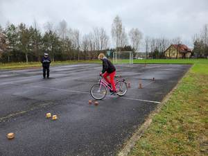 Policjanci podczas turnieju BRD z uczniami  na placu podczas jazdy rowerem oraz podczas wręczania nagród