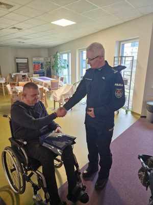Komendant Wojewódzki Policji w Łodzi  podczas spotkania z policjantem w szpitalu. Komendant stoi policjant siedzi na wózku inwalidzkim.
